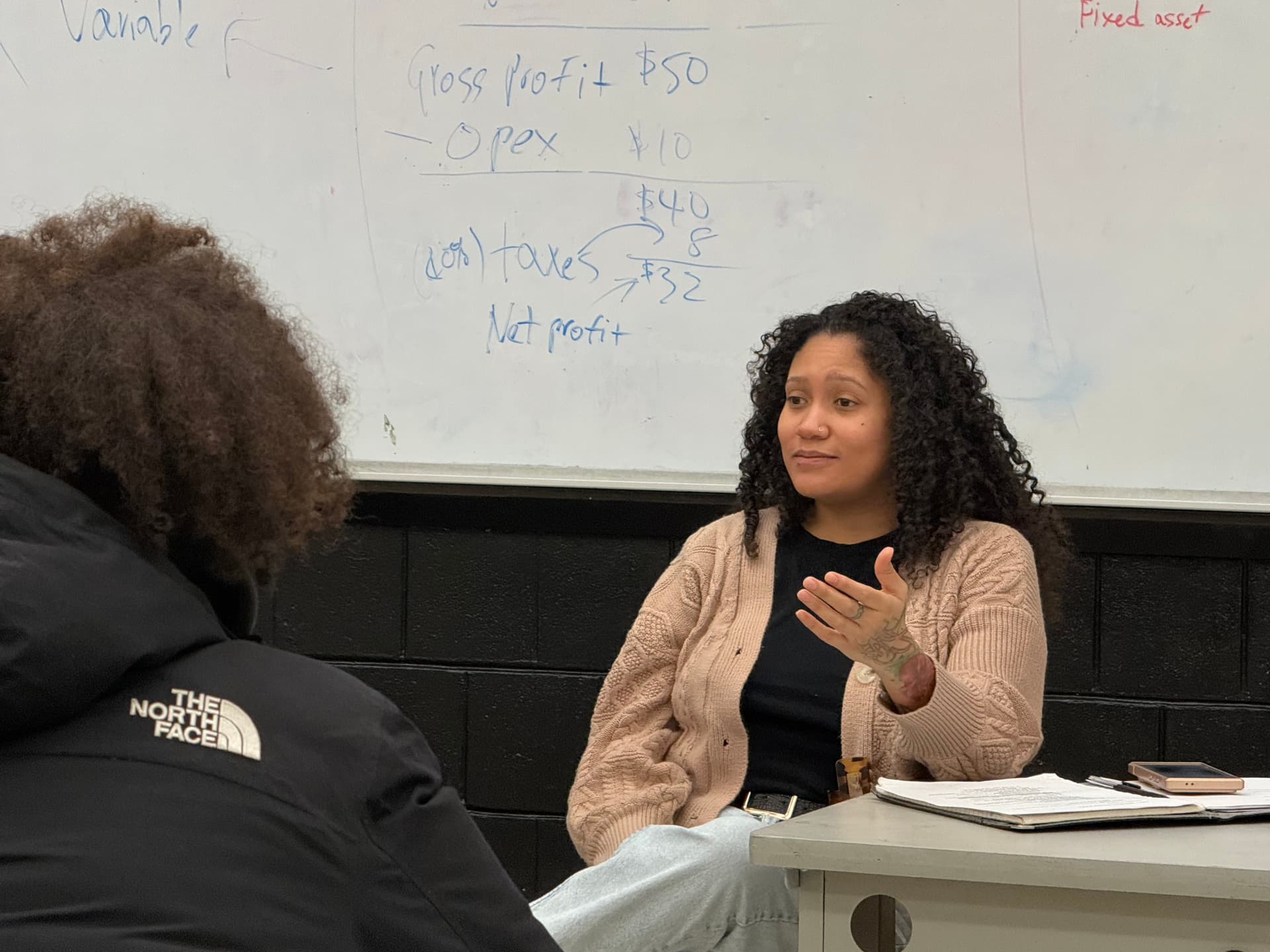 A REBELS facilitator explaining net profit at the whiteboard