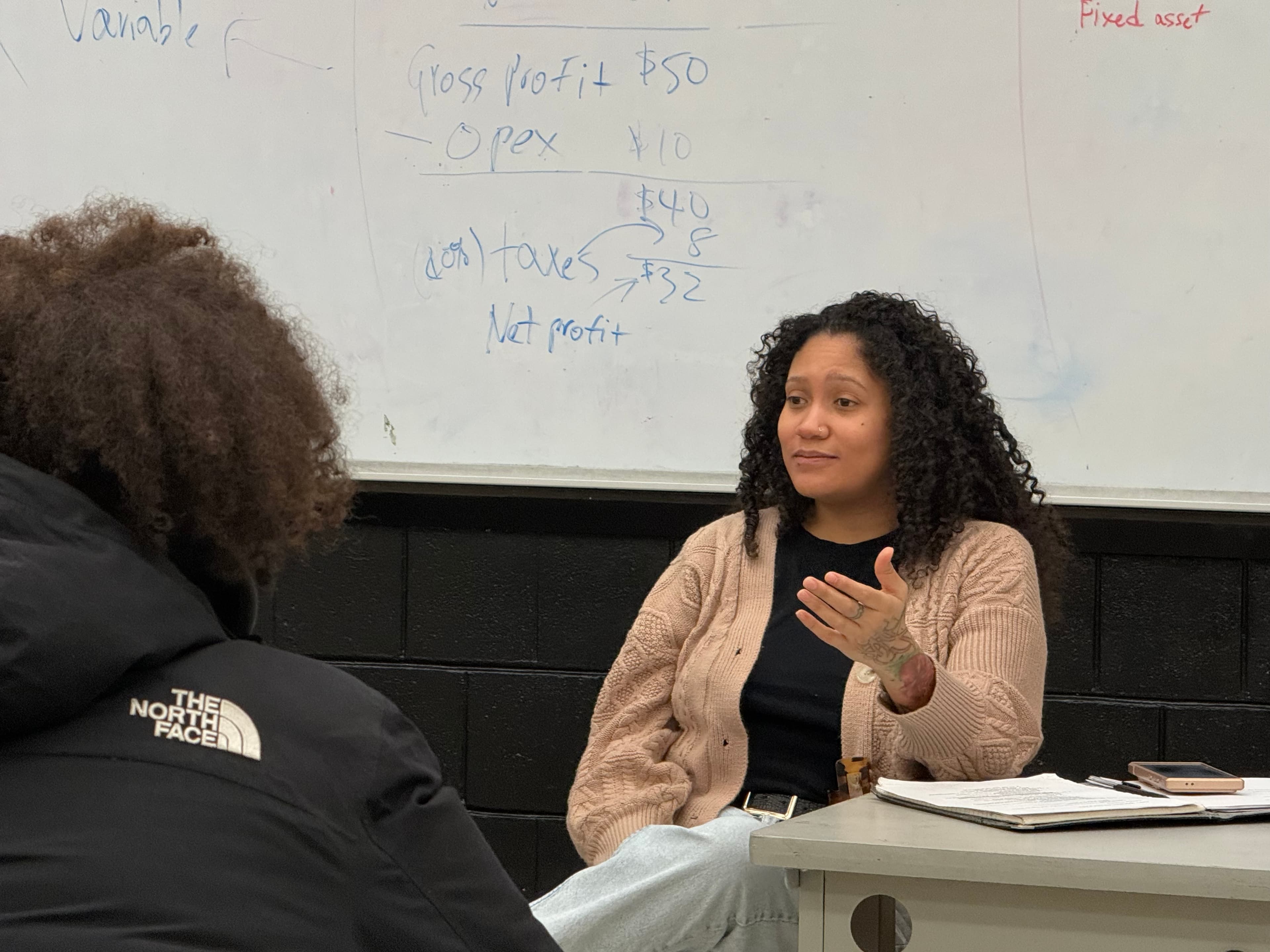 A REBELS facilitator working through a financial concept on the whiteboard with a student