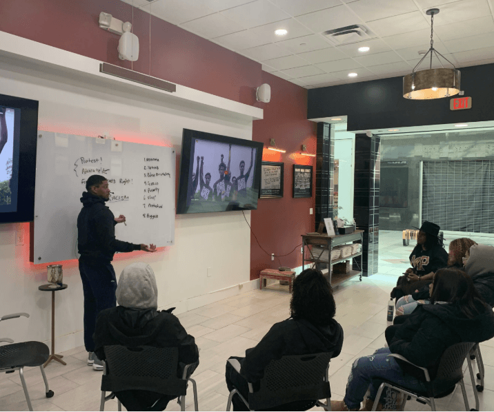 A REBELS facilitator leading a workshop presentation for a seated audience
